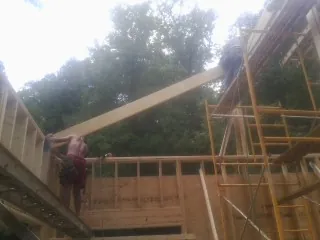 Carpenter raising a rafter beam on a new second story frame in Elkton
