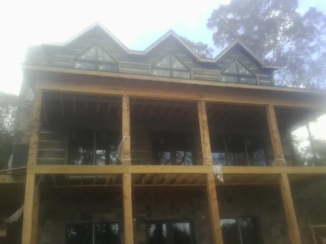 Dormers and porch framing on a large log home under construction — Roof Coating work by our crew in Elkton